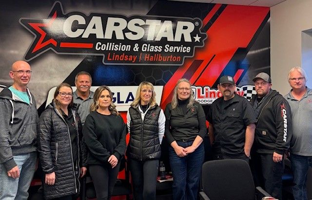 CARSTAR Collision & Glass Service team photo with company logo backdrop