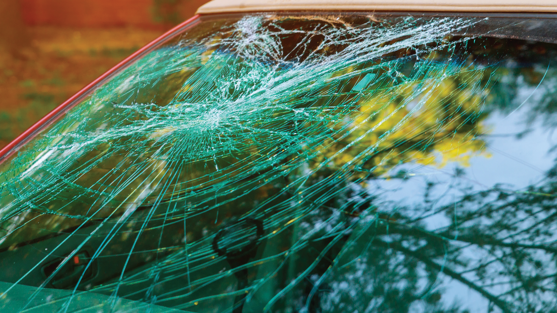 Cracked windshield with intricate green-tinted glass fracture patterns