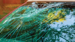 Cracked windshield with intricate green-tinted glass fracture patterns