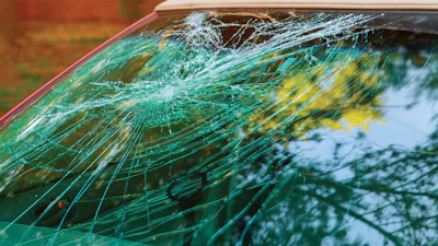 Cracked windshield with intricate green-tinted glass fracture patterns