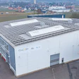 White industrial building with solar panels, aerial view of modern facility