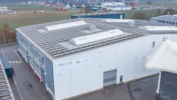 White industrial building with solar panels, aerial view of modern facility