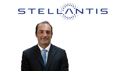 Professional headshot of male executive in dark suit with blue tie, Stellantis logo visible above