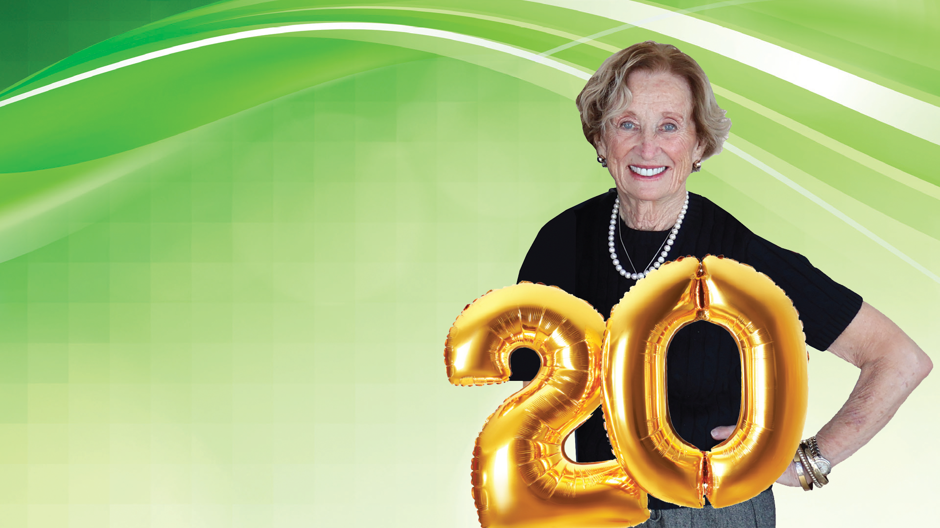 Smiling senior woman celebrating with gold '20' anniversary balloons