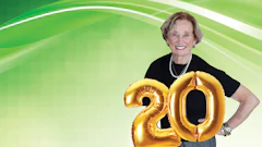 Smiling senior woman celebrating with gold '20' anniversary balloons
