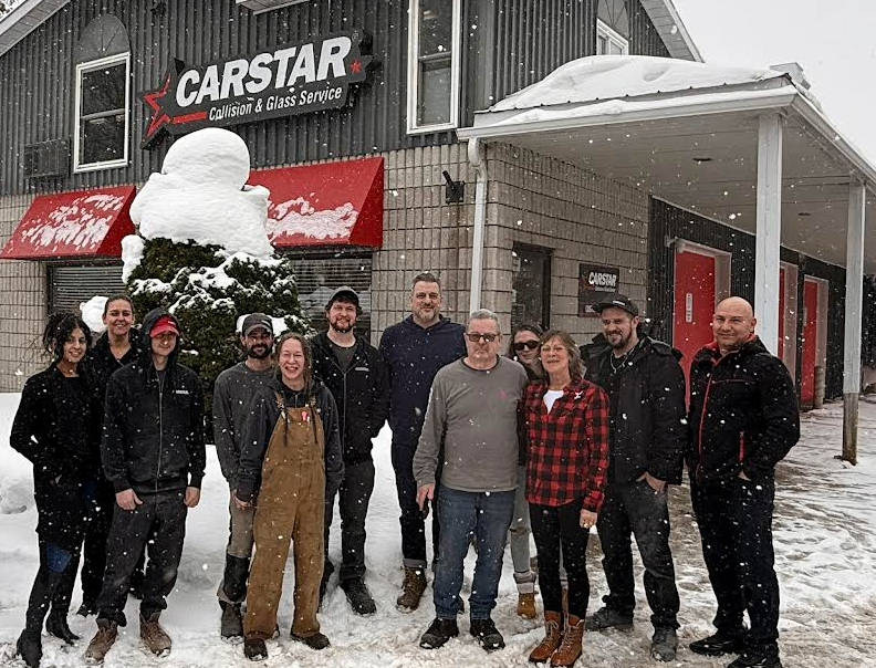 CARSTAR collision repair team standing outside snowy shop in winter