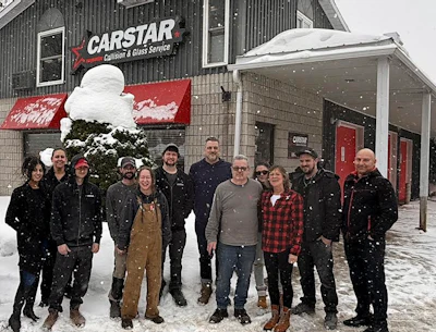 CARSTAR collision repair team standing outside snowy shop in winter