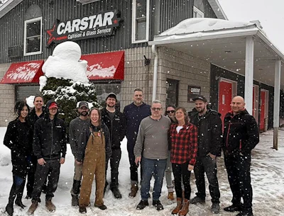 CARSTAR collision repair team standing outside snowy shop in winter