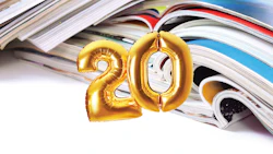 Gold metallic number balloons '20' resting on scattered magazines and publications