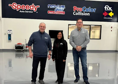Three professionals standing in automotive service center with Speedy, Novus, ProColor, and Fix Auto logos