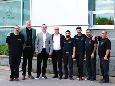 Mercedes-Benz team of eight employees posing together outside corporate building