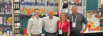 Four professionals at Commercial Norms trade show booth with product displays