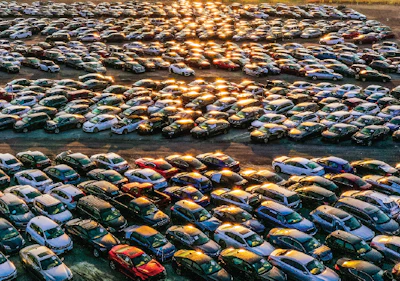Aerial view of crowded parking lot with cars reflecting golden sunset light