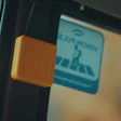 Yellow UWB wireless tag mounted on vehicle window near blue information sign