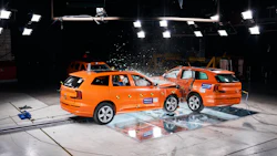 Two orange Volvo vehicles in a crash test collision under bright studio lights