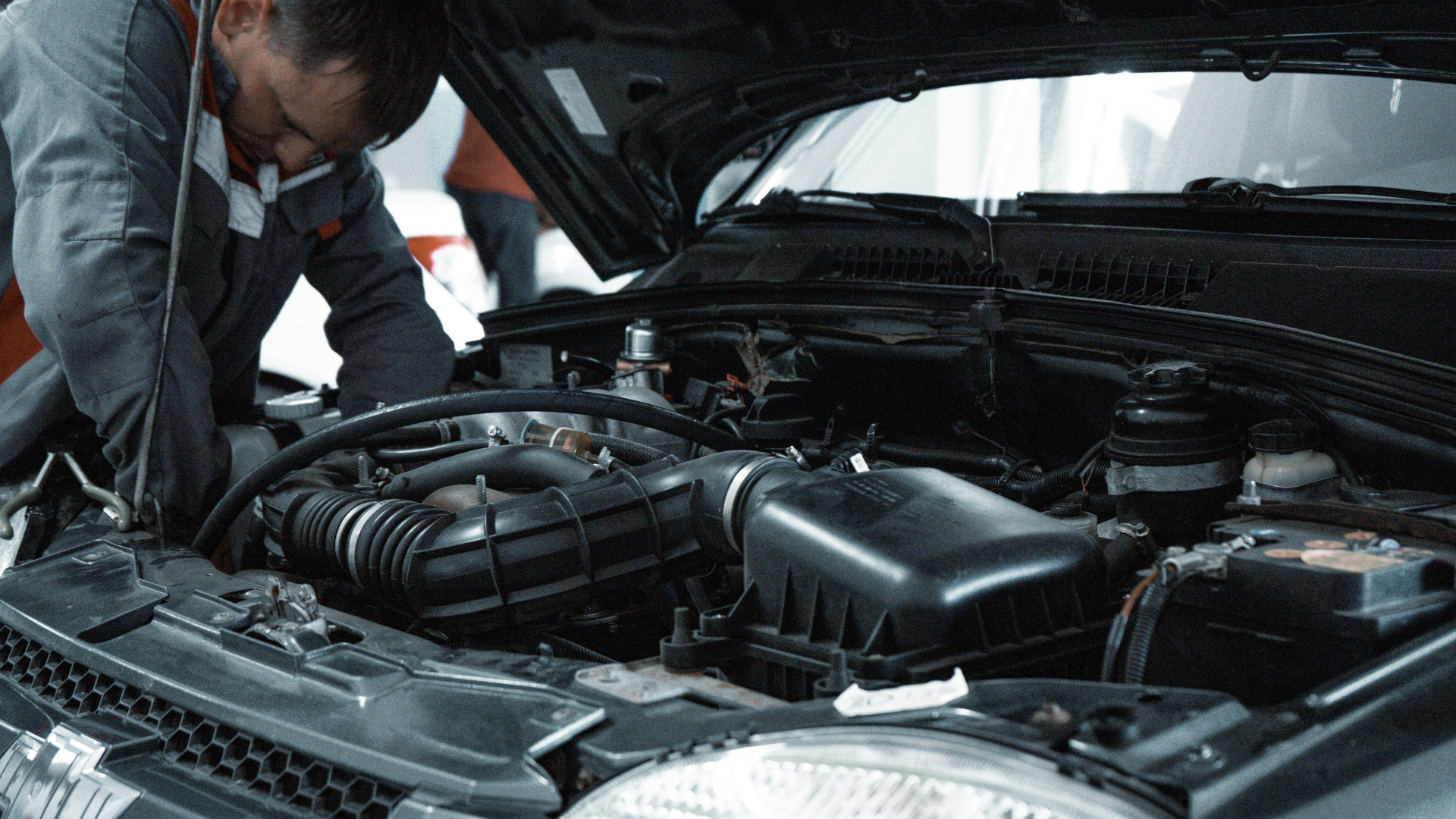 Mechanic examining car engine under open hood in automotive repair shop