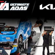 Blue Kia vehicle undergoing performance testing on dyno platform with technicians in professional garage setting