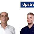 Two professional men smiling at camera with Upstream company branding