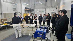 Group of people in black attire gathered in warehouse for equipment demonstration or training session