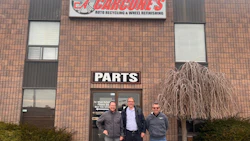 Three men stand outside Cargone's Auto Recycling & Wheel Refinishing storefront with brick facade and signage