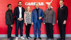 Six professionals posing together in front of red CARSTAR branded wall signage