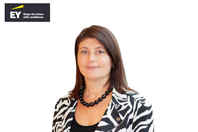 Professional woman with long brown hair wearing a zebra-patterned blazer and black beaded necklace, with EY company logo displayed