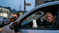 Person in parked car holding parking permit with Toronto police vehicle and urban street scene in background