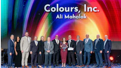 Group of business professionals at corporate event with colorful gradient backdrop displaying Colours, Inc. branding