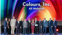 Group of business professionals at corporate event with colorful gradient backdrop displaying Colours, Inc. branding