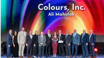 Group of business professionals at corporate event with colorful gradient backdrop displaying Colours, Inc. branding