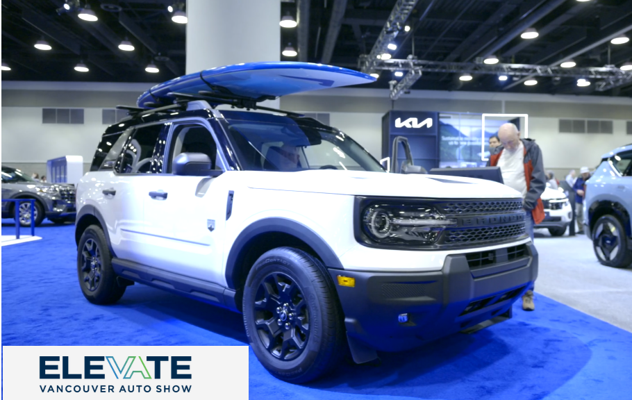 White and blue Kia EV9 SUV with roof rack displayed at Vancouver Auto Show event