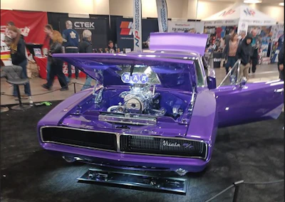 Purple custom car with open hood displaying chrome engine at automotive show