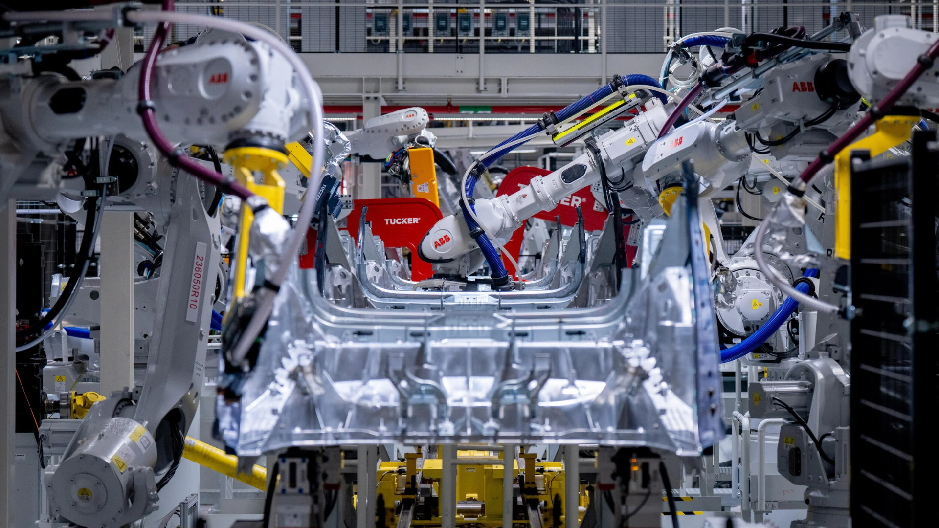 Industrial robotic arms assembling automotive vehicle chassis in factory with precision welding equipment