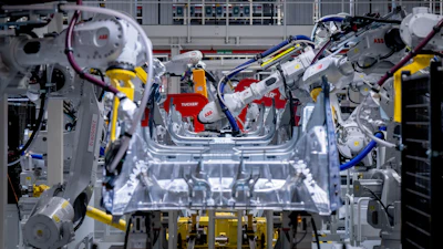 Industrial robotic arms assembling automotive vehicle chassis in factory with precision welding equipment