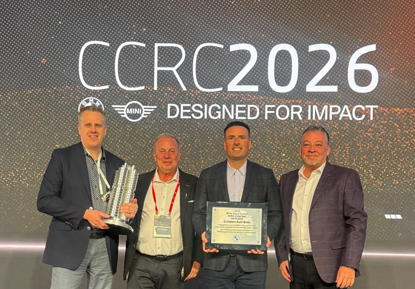 Four men in business attire at CCRC2026 awards event, one holding a certificate and trophy