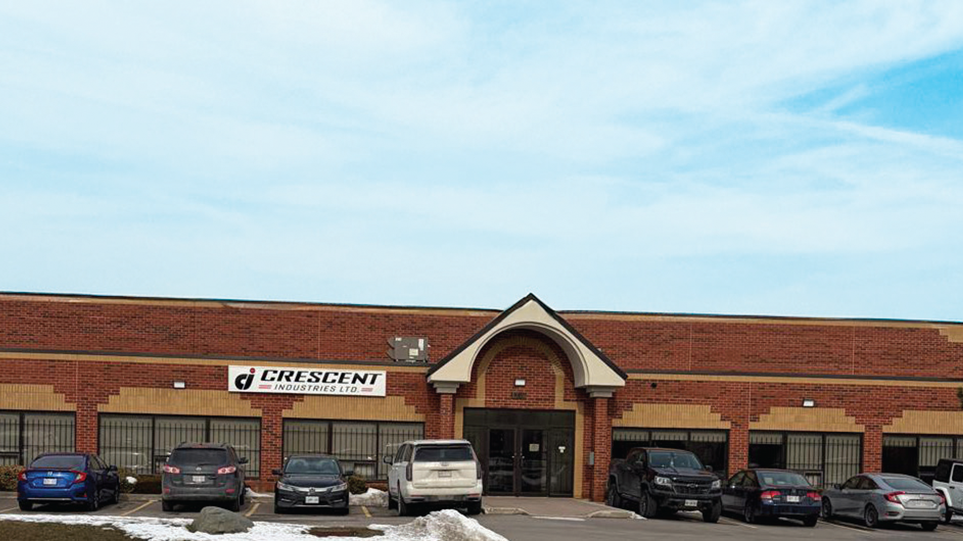 Crescent automotive service facility with red brick exterior, multiple garage bays, and parked vehicles in front