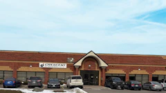 Crescent automotive service facility with red brick exterior, multiple garage bays, and parked vehicles in front