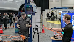 Attendees interact at an automotive trade show with vehicle lifts and NAPA branded booth visible