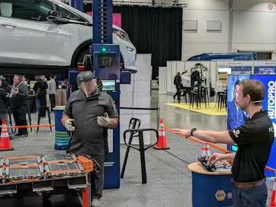 Attendees interact at an automotive trade show with vehicle lifts and NAPA branded booth visible