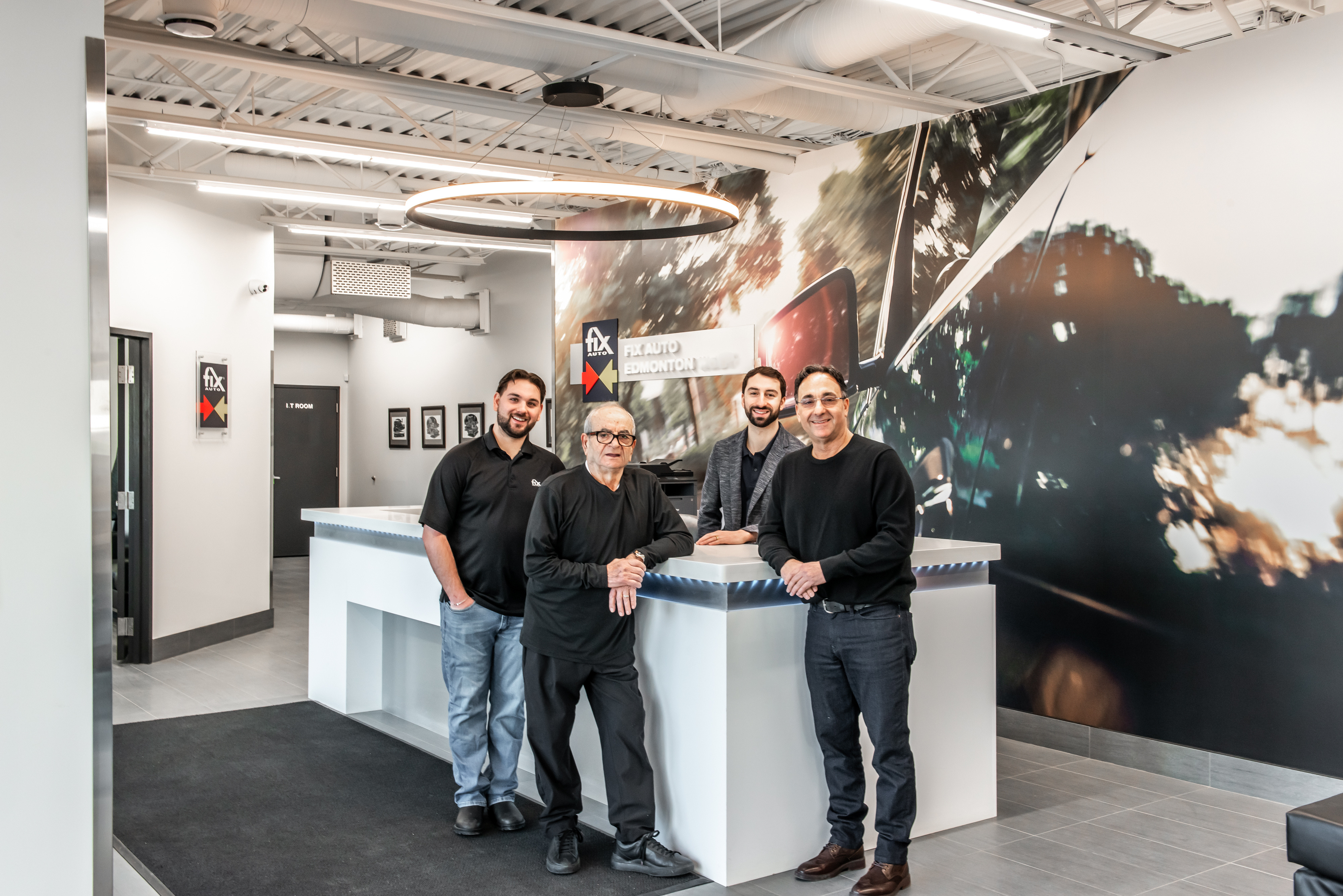 Four team members in black shirts standing at a modern white reception desk in a bright office space
