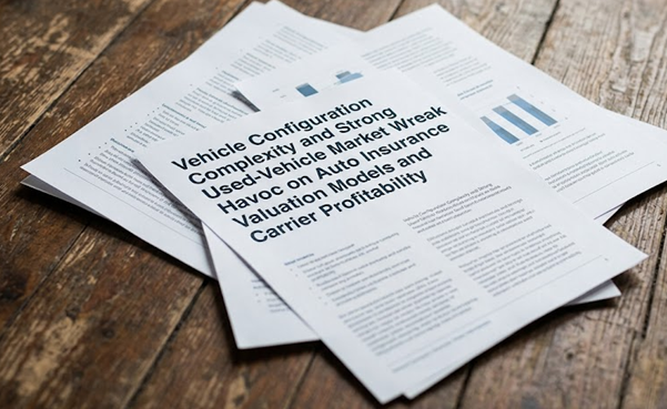 Business documents with vehicle configuration and insurance information spread on wooden surface