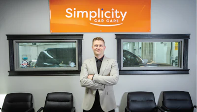 Professional man in blazer standing in car care showroom with Simplicity Car Care branding