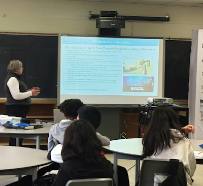 Instructor presenting EV battery recycling information to students in a classroom using a projected slide display.