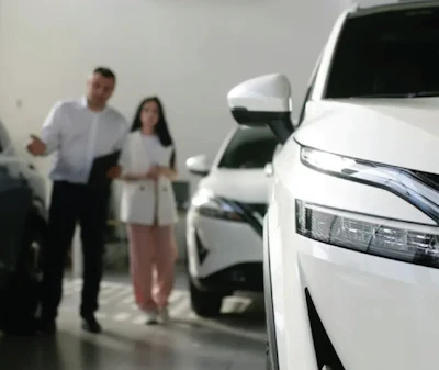 Two people standing in a parking garage near white vehicles during what appears to be a car viewing or dealership visit