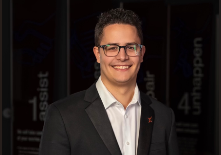 Professional man in glasses and dark blazer smiling at camera