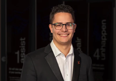 Professional man in glasses and dark blazer smiling at camera