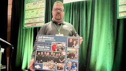 Man holding commemorative poster with photos at event with sponsor banners