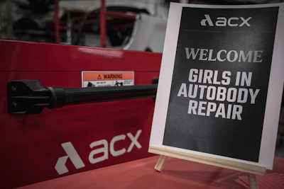 ACXS branded red equipment with welcome sign promoting girls in autobody repair program