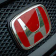 Red Honda emblem on vehicle grille with chrome trim