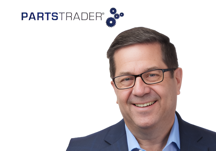 Professional headshot of smiling man in glasses and navy blazer with PartsTrader logo
